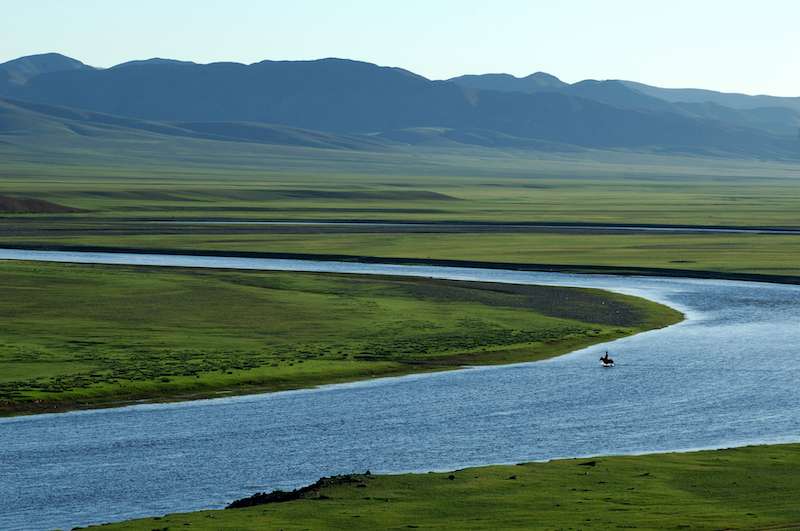 Un cavaliere attraversa fiume in Mongolia