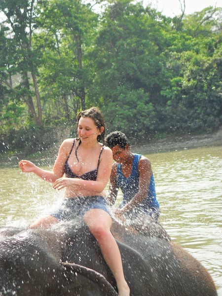 una turista si diverte con gli elefanti al bagno a fine giornata nel parco nazionale del Chitwan in nepal