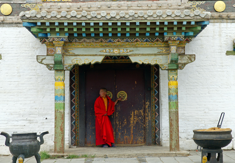 Un giovane monaco sul portone di ingresso del tempio buddista del Monastero di Erdene Zuu a Kharkhorin in Mongolia